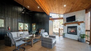 Un salon chaleureux avec une cheminée, des meubles en osier et un ventilateur de plafond.
