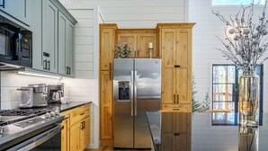 Une cuisine moderne avec des meubles en bois, des appareils en acier inoxydable et un plan de travail noir.