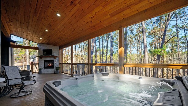 Un bain à remous sur une terrasse en bois, avec une cheminée et des sièges d’extérieur.