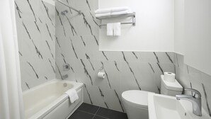 A modern bathroom with a bathtub, toilet, and shower area. - The Pas Motel (The Pas)