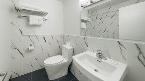 A modern bathroom with a toilet, sink, and towel rack. - The Pas Motel (The Pas)