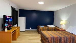 A hotel room with two beds, a TV, a refrigerator, and a desk. - The Pas Motel (The Pas)
