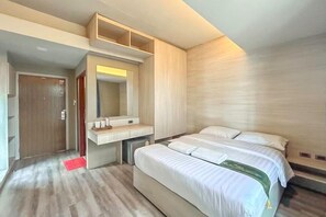 Una habitación de hotel con una cama, un escritorio, un espejo y una puerta.