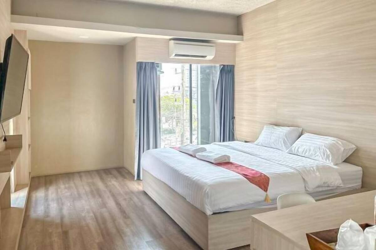 A modern hotel room with a large bed, a desk, and a TV.