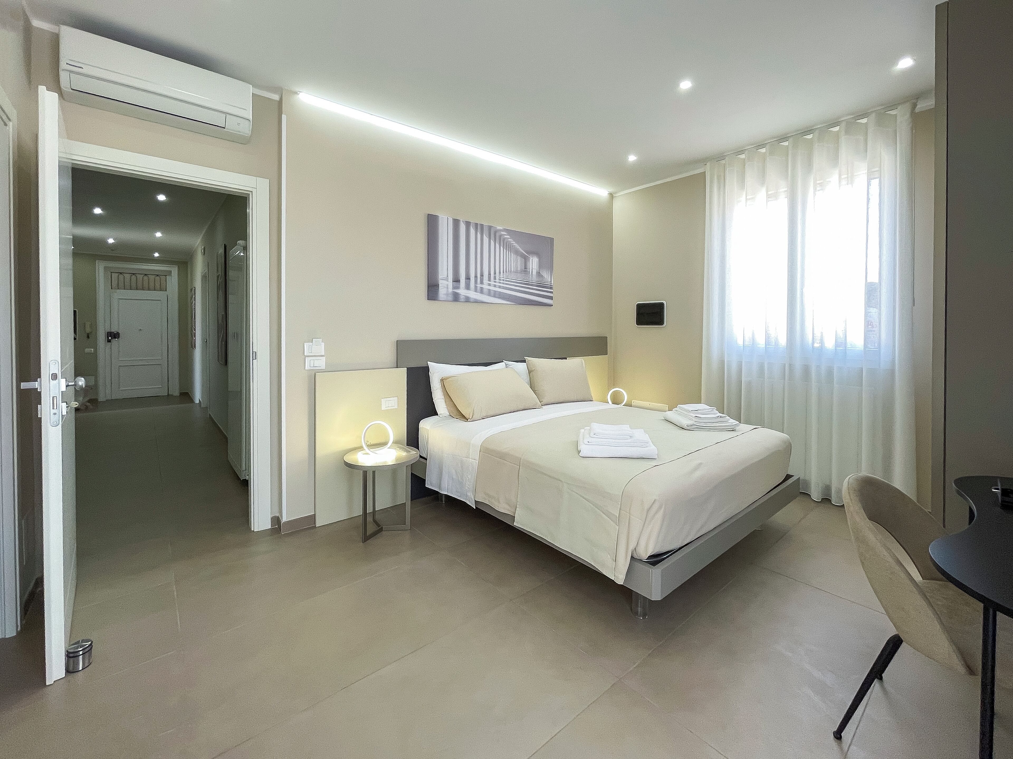 Camera d'albergo con un letto grande, comodini, una scrivania e vista sulla città dalla finestra.