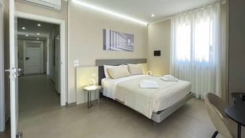 Camera d'albergo con un letto grande, comodini, una scrivania e vista sulla città dalla finestra.