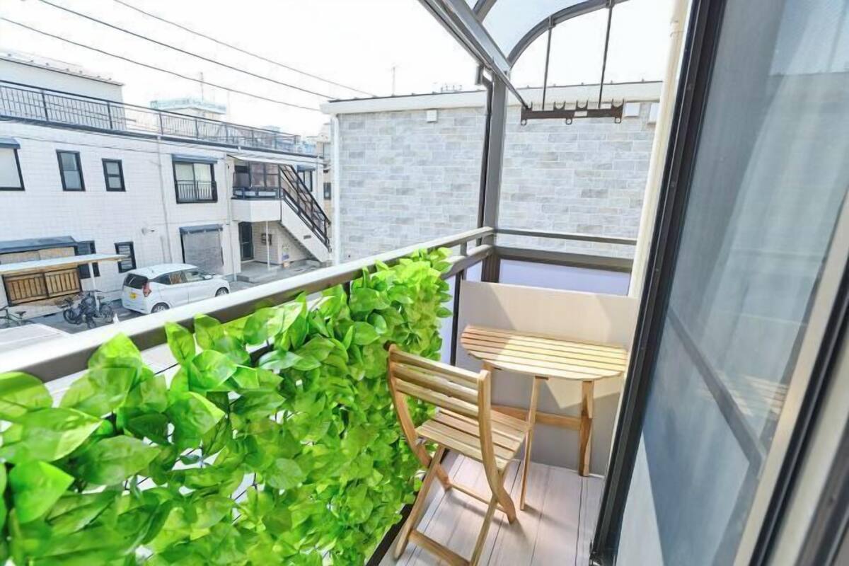 A balcony with a wooden chair, a small table, and green plants.