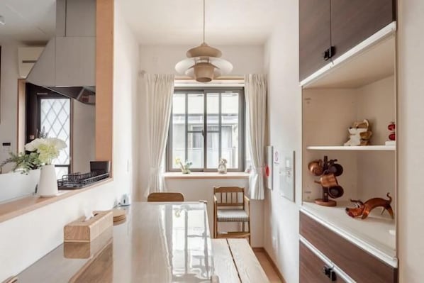 Una cocina moderna con una isla central, una mesa de comedor y un ventanal con cortinas.
