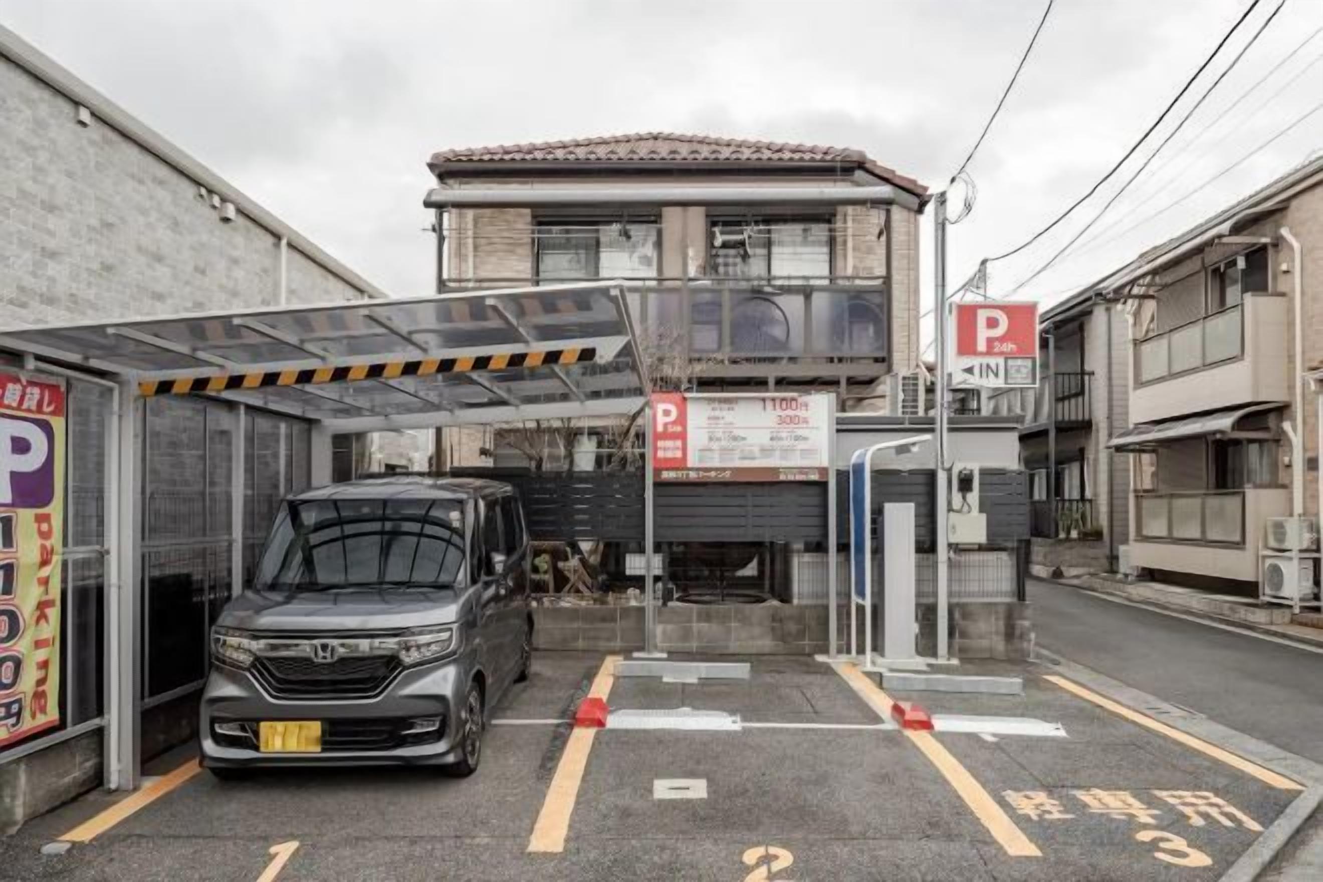 A parking garage entrance with a car, a covered area, and a building with a red 'P' sign.