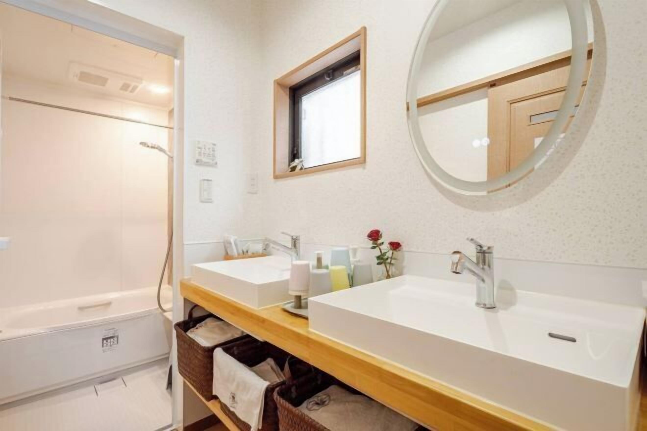 A bathroom with two sinks, a shower, a window, and a mirror.