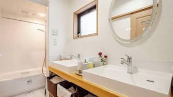 A bathroom with two sinks, a shower, a window, and a mirror.