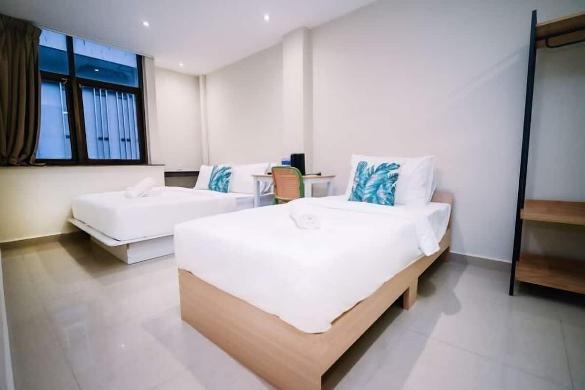 A hotel room with two beds, a desk, and a window with curtains.