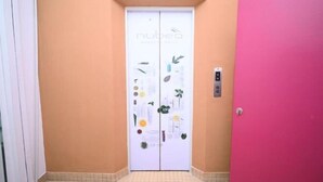 A hallway with a white door featuring botanical decorations and a control panel. - Swing & Pillows - Times Square, Bukit Bintang (Kuala Lumpur)