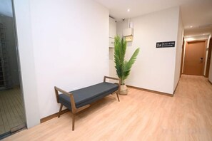 A hallway with a bench, a potted plant, and a door with a sign. - Swing & Pillows - Times Square, Bukit Bintang (Kuala Lumpur)