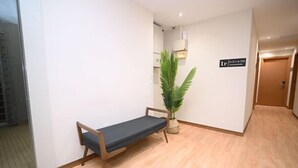 A hallway with a wooden bench, a potted plant, and a sign indicating room number 1F. - Swing & Pillows - Times Square, Bukit Bintang (Kuala Lumpur)