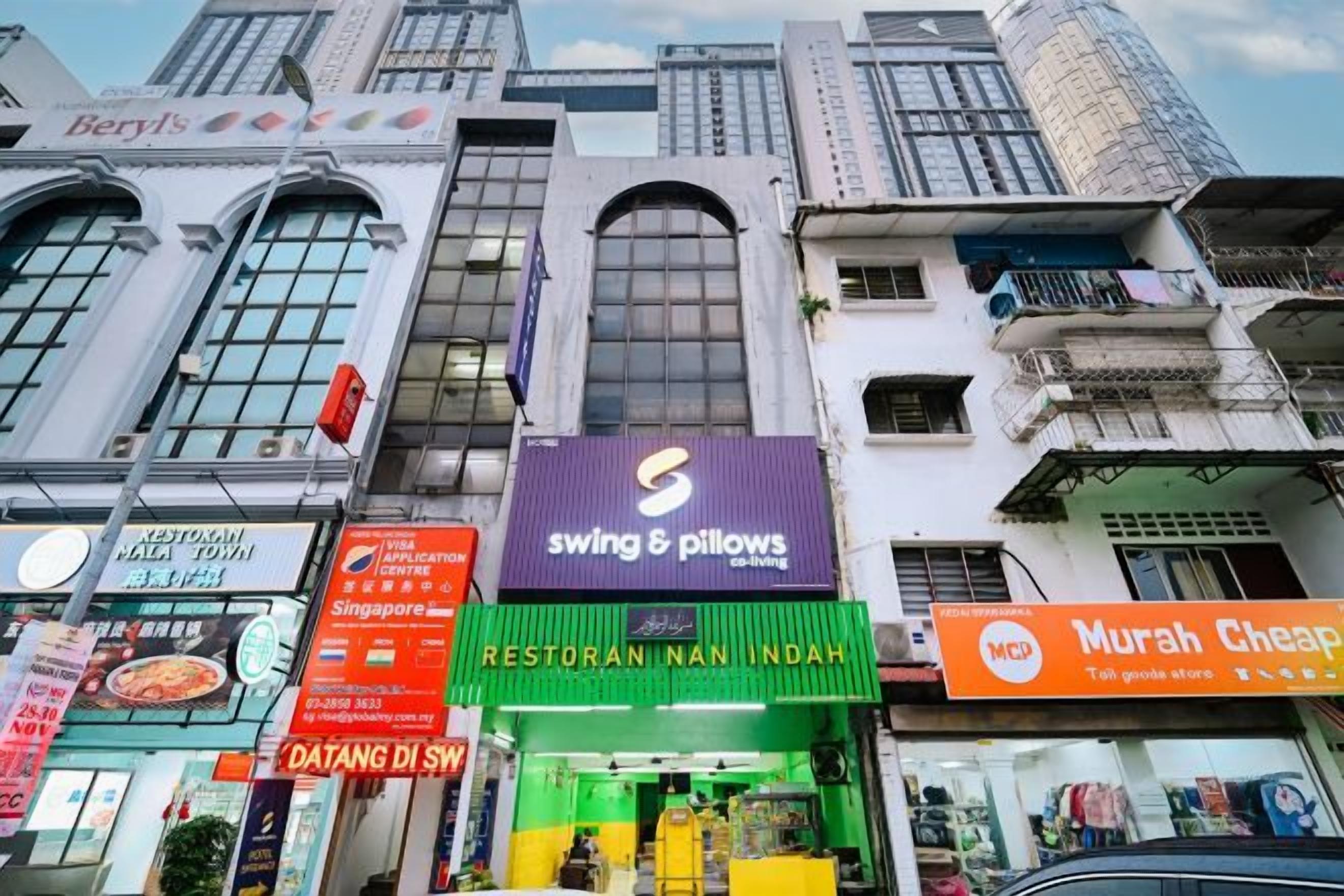 A street view with various storefronts, including a restaurant named 'Restoran Nan Indah' and a store called 'Murah Cheap.'