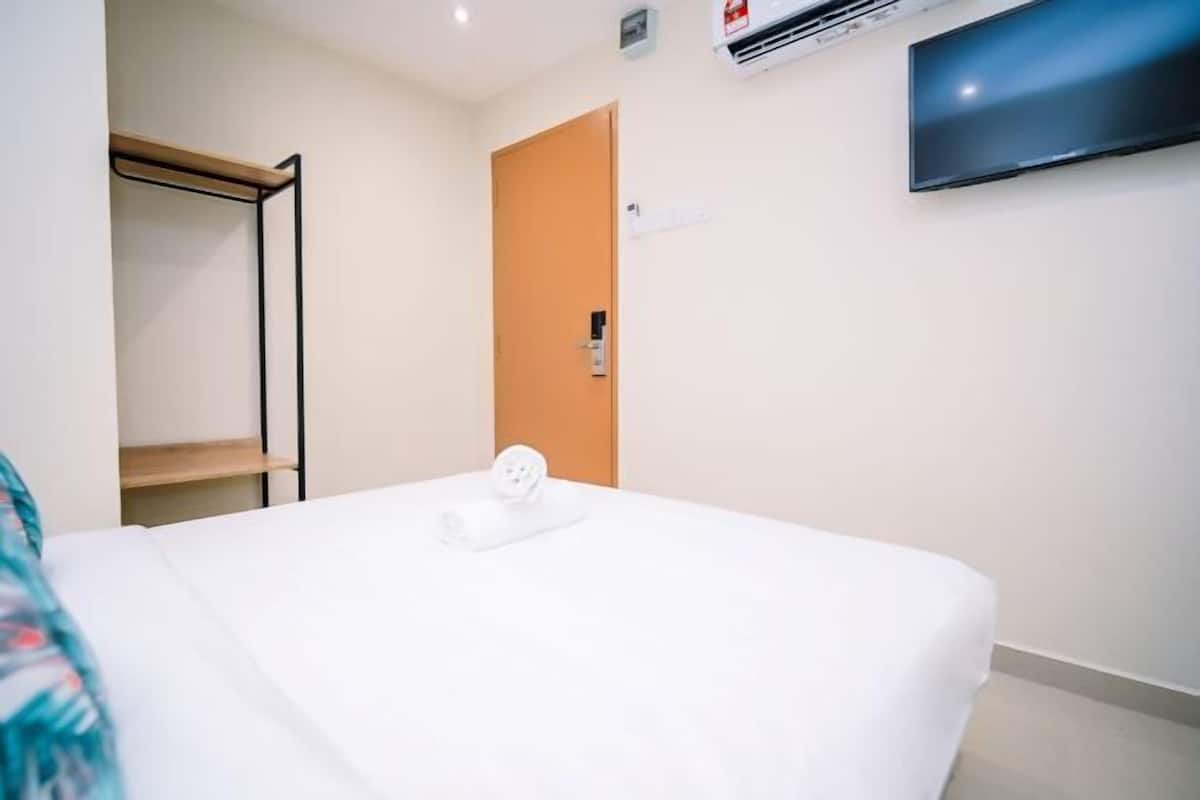 A hotel room with a bed, a television mounted on the wall, and a door.