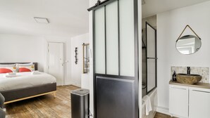 Un dormitorio moderno con cama, mesita de noche y un espejo grande.
