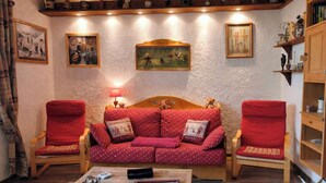 A cozy living room with a red sofa, two red armchairs, a wooden coffee table, and a fireplace.