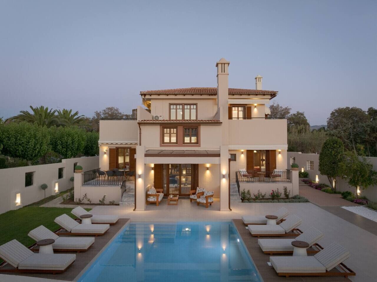 Une maison à deux étages avec une piscine, un espace extérieur aménagé pour se détendre et une terrasse bien éclairée.