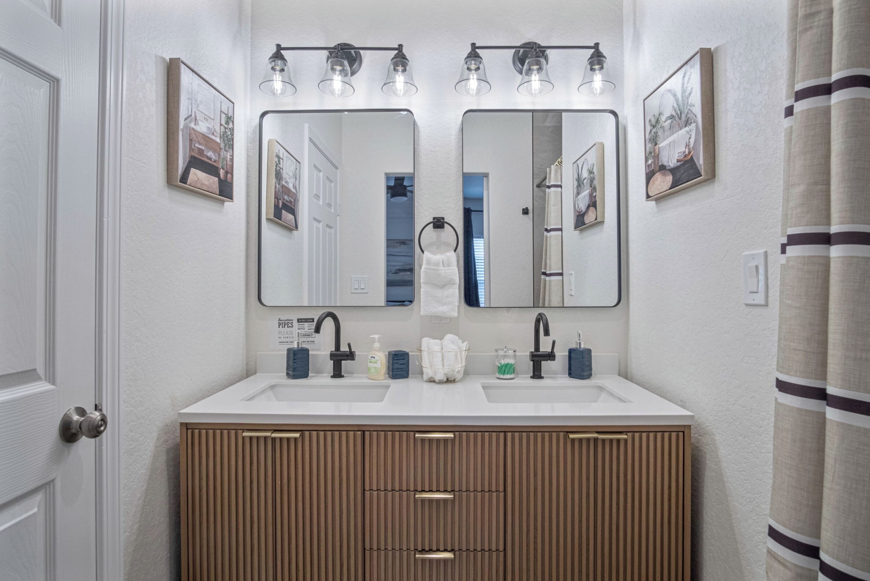 Een badkamer met een wastafel, een houten opbergmeubel en twee spiegelwanden.