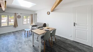 Un salon moderne comprenant un coin repas, un canapé, une table et une lucarne.