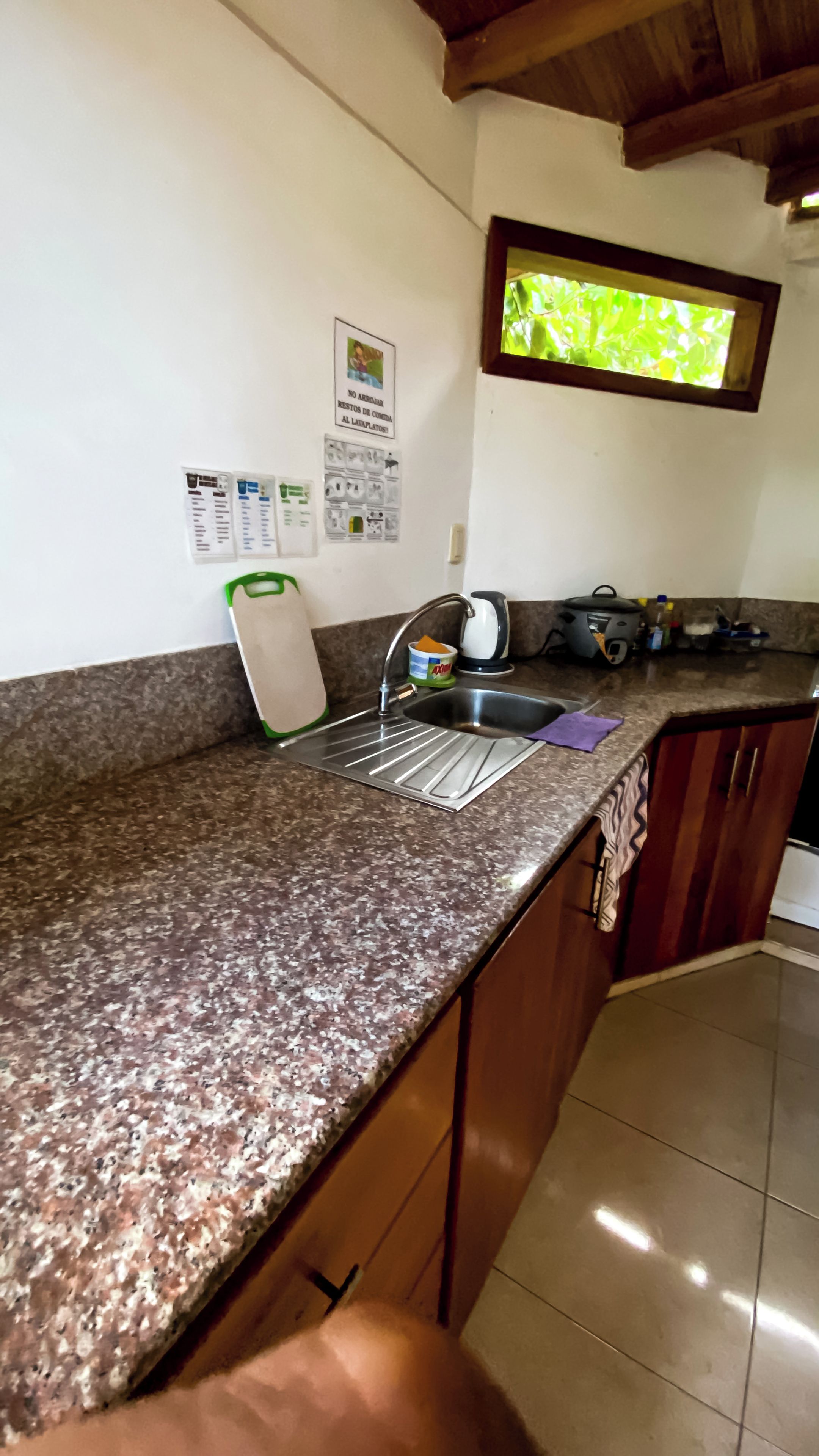 Una cocina con encimera de granito, pileta de acero inoxidable y muebles de madera.