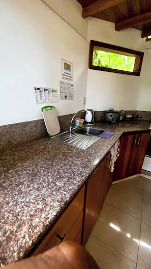 Una cocina con encimera de granito, pileta de acero inoxidable y muebles de madera.