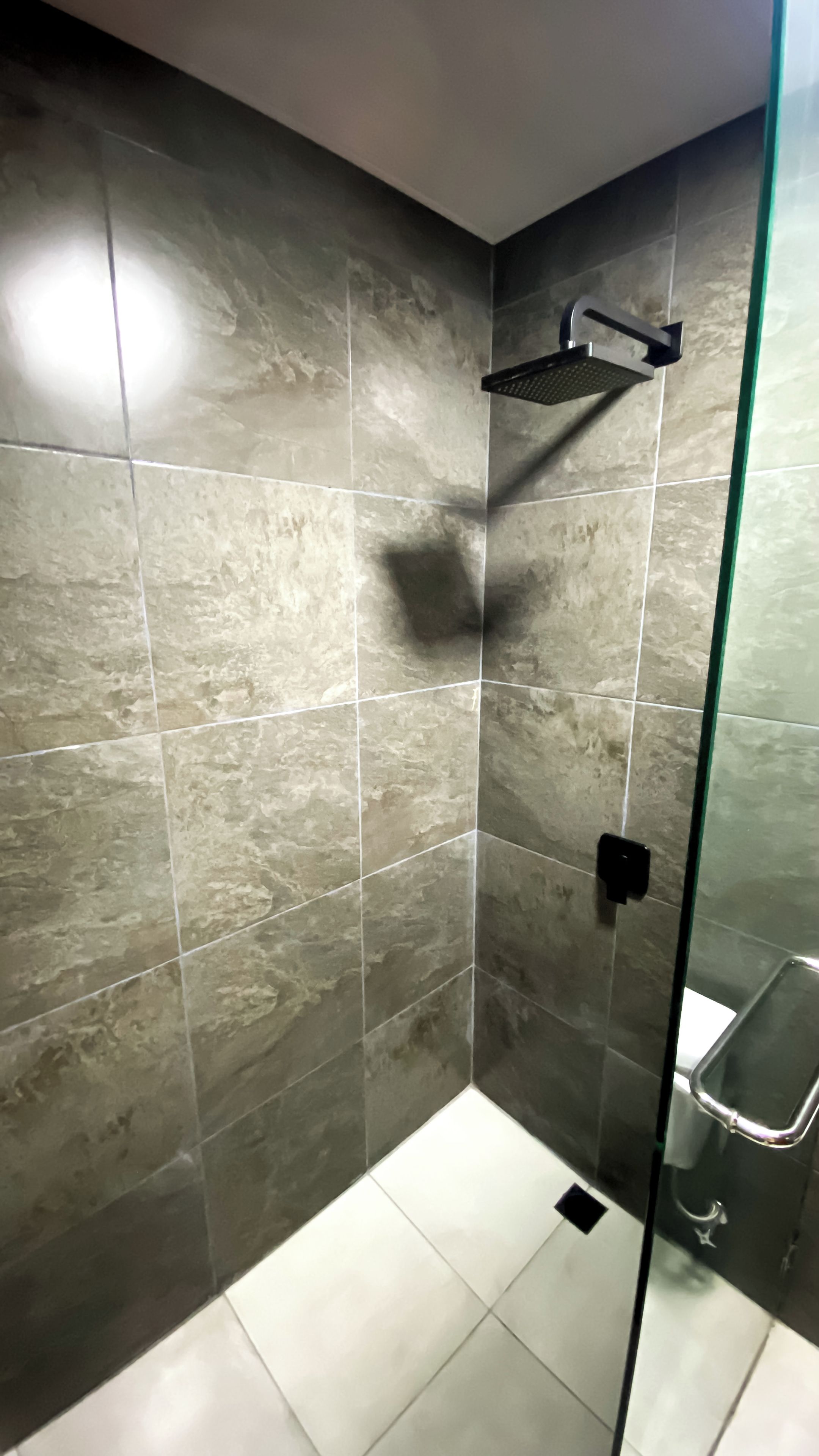 A shower area with a glass door, tiled walls, and a handheld showerhead.