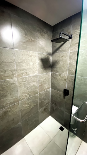 A shower area with a glass door, tiled walls, and a handheld showerhead.