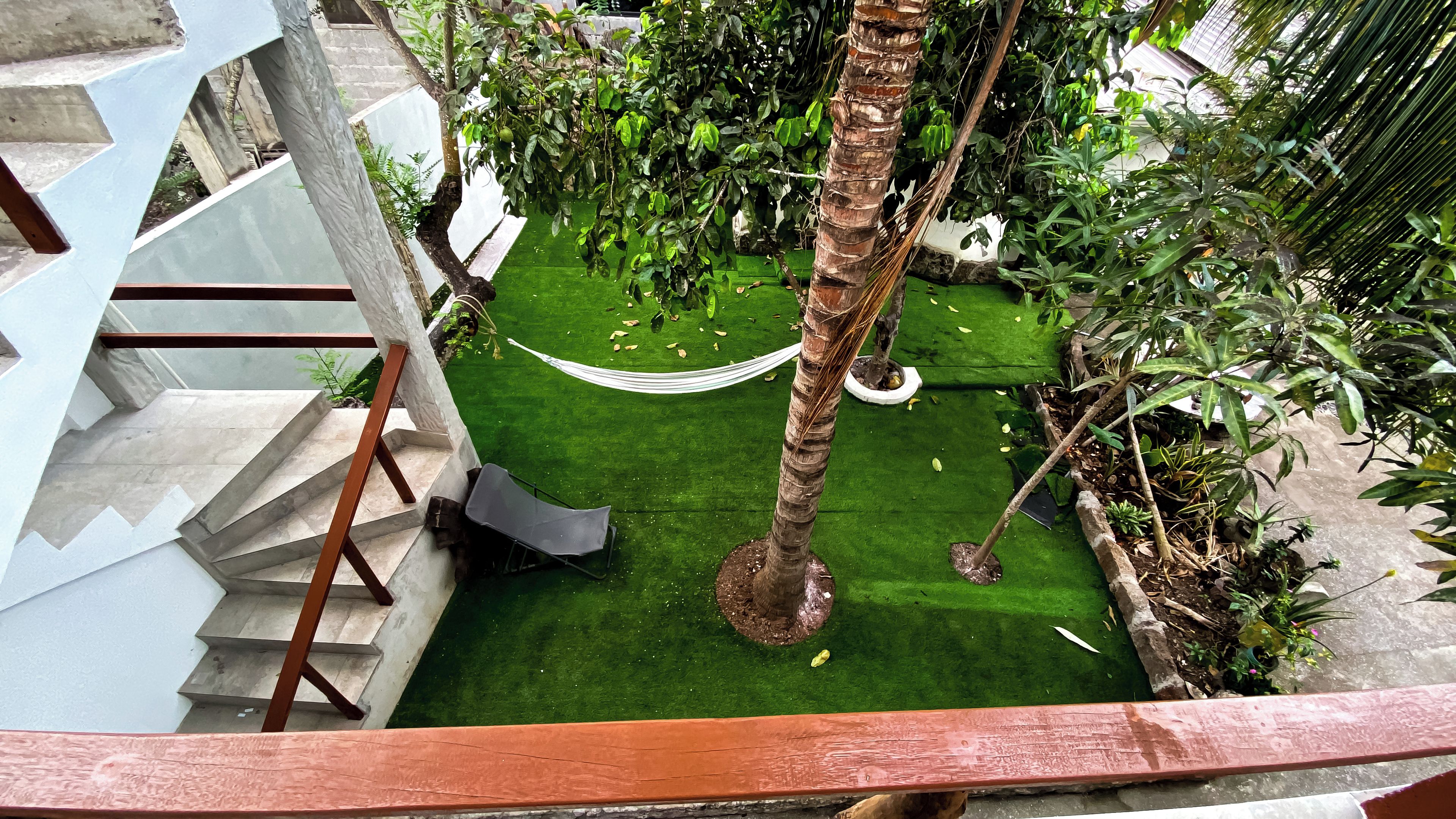 Un jardin sur le toit, avec un hamac, des palmiers et un escalier.