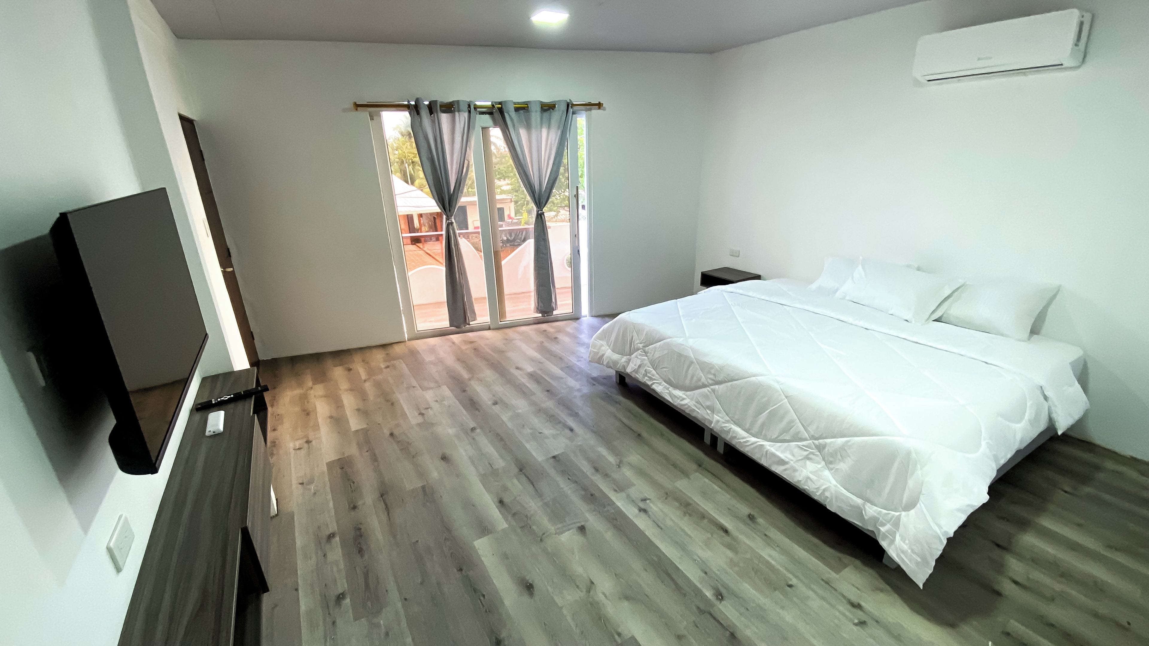 Una habitación de hotel con cama, televisión, escritorio y ventana con cortinas.