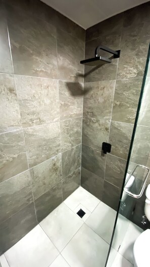 A shower area with a glass door, tiled walls, and a showerhead.