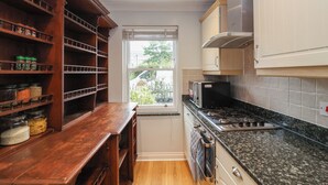 Eine kompakte Küche mit Holzböden, einem eingebauten Ofen und einem Fenster mit Blick ins Freie.