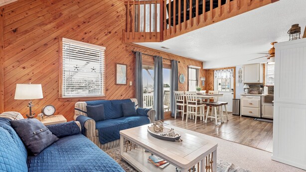 Een gezellig cabin interieur met houten plafond, een eethoek, een keuken en een woonkamer met een blauwe bank en een salontafel.