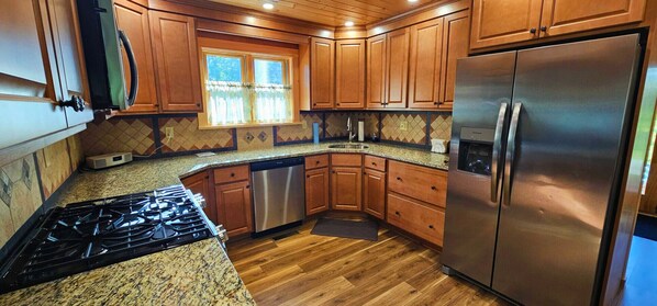 A kitchen with wooden cabinets, a stainless steel refrigerator, a dishwasher, and a granite countertop. - Whitetail Ledge Cabin*ATV Access*Community Dock*Lake Access*Washer/dryer (Greenville)