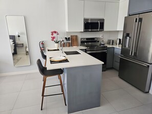 Una cocina moderna con una isla central, electrodomésticos de acero inoxidable y un diseño minimalista.