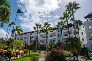 A resort with multiple-story buildings, palm trees, and a well-maintained garden.