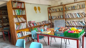 A library with bookshelves filled with books, a chalkboard with numbers, and various educational toys on a table. - Sadili Oval B & B (Nairobi)