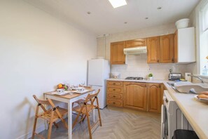 Une cuisine compacte avec des meubles en bois, un réfrigérateur blanc, une table à manger avec des chaises et un four encastré.