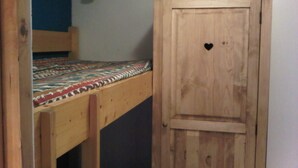 A wooden bunk bed with a patterned bedspread and a wardrobe with a heart-shaped cutout. - Les Ménuires, on skis (Saint Martin de Belleville)