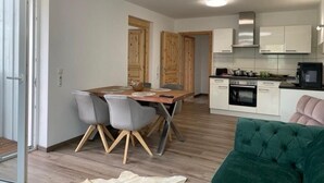 Ein modernes Apartment mit Essbereich, Küche und einem grünen Sofa.