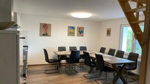 Ein Konferenzraum mit langem Tisch und Stühlen, weißen Wänden und Kunstwerken an den Wänden.