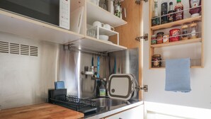 A compact kitchen with a stainless steel range hood, a toaster, and a variety of kitchen utensils and appliances. - Over Village Studio (Cambridge)