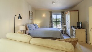 A bedroom with a bed, a desk, a chair, a lamp, and a television. - Over Village Studio (Cambridge)