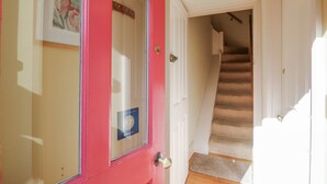A hallway with a red door, a coat rack, and a staircase leading to another room. - Over Village Studio (Cambridge)