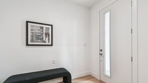 Ein schlichter Raum mit einer Bank, einem gerahmten abstrakten Kunstwerk und einer Tür mit Fenster.