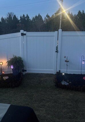 A fenced backyard with a lawn, a potted plant, and a small table with a lamp. - 2 bedroom, 2.5 in charming Trinity privacy, I-85 and downtown High Point. (Trinity)