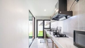 Een moderne keuken met een gasfornuis, een afzuigkap en een groot raam.