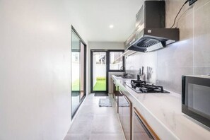 Une cuisine moderne équipée d’une cuisinière à gaz, d’une hotte aspirante et d’une grande fenêtre.